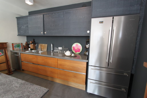 zwarte keuken met kookeiland en doorlopend houtpatroon, meubelmaker amsterdam cabinetmaker custom furniture op maat gemaakt maatwerk meubels